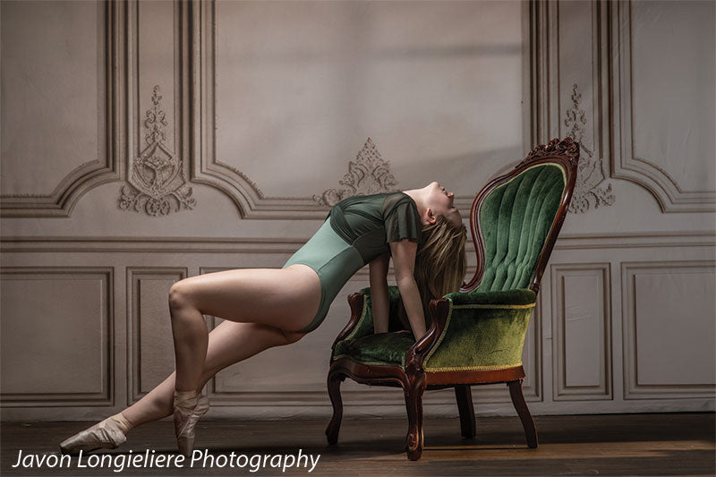 Elegant French Panel Wall photography backdrop with an antique green velvet armchair, shown with a young ballet dancer arching back against the chair en pointe CP-8744