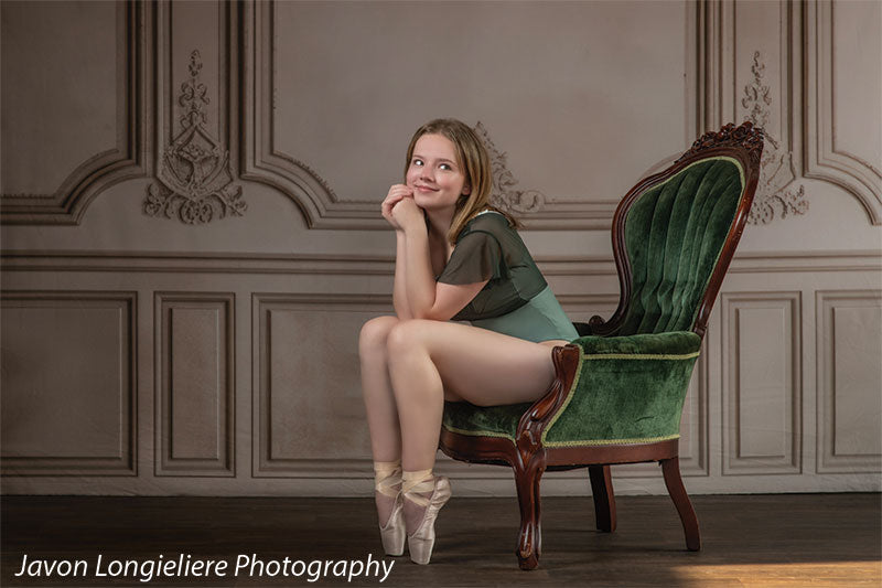 Elegant French Panel Wall photography backdrop with an antique green velvet armchair, shown with a young ballet dancer seated on the chair looking upward with hand to her chin CP-8744