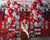 Smiling girl posing in front of a full view of the firehouse cake smash backdrop featuring festive balloons, red garage doors, and dalmatian plush toys.
