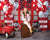Girl sitting on a stool in front of a firehouse-themed backdrop with red and white balloons and firefighter stuffed animals.