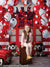Happy girl sitting front and center with red and white balloons and firehouse backdrop featuring stuffed dalmatians and red fire station doors.