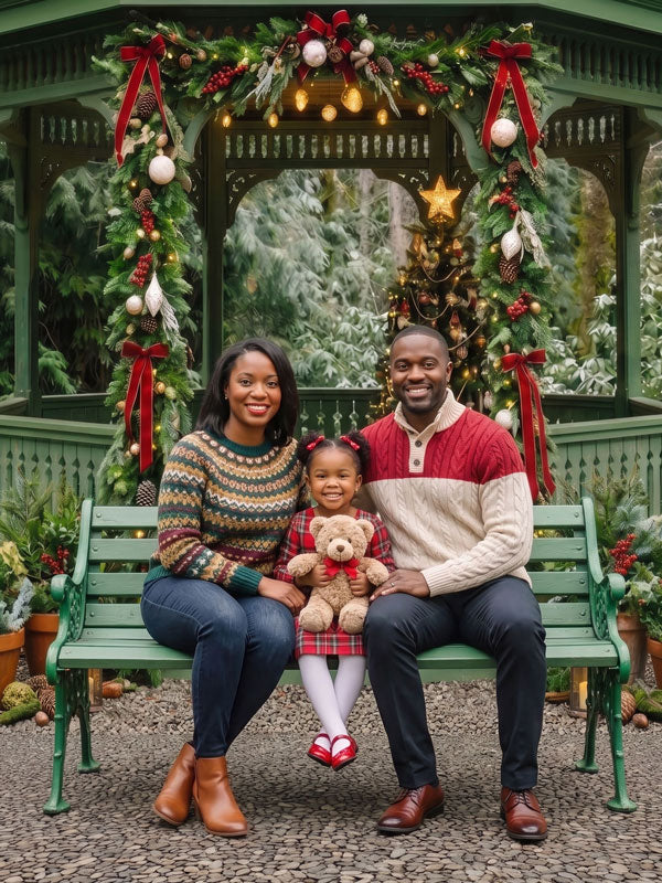Garden Noel green Christmas gazebo with garland and wreaths photography backdrop shown with a family of three seated on a green bench CP-8900