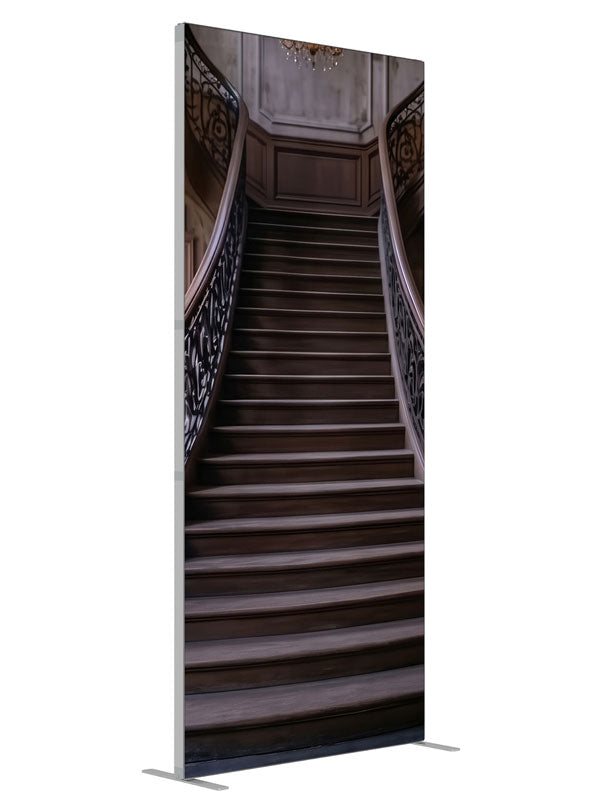 An opulent mansion foyer staircase with iron scroll railings and lit crystal chandeliers, 3ft photography backdrop panel for Denny StudioEdge silicone edge frame, angled view