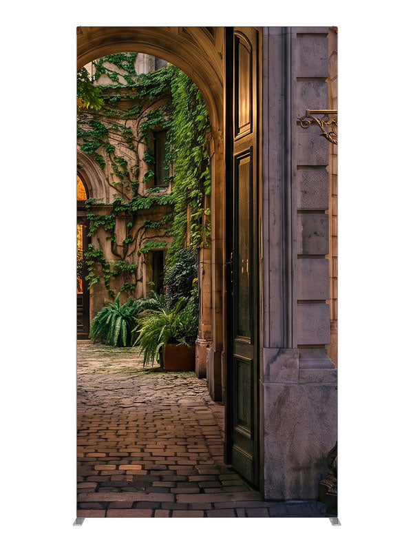 Stone archway opening onto an ivy-covered European courtyard with a glowing iron street lamp, 4ft photography backdrop panel for Denny StudioEdge silicone edge frame