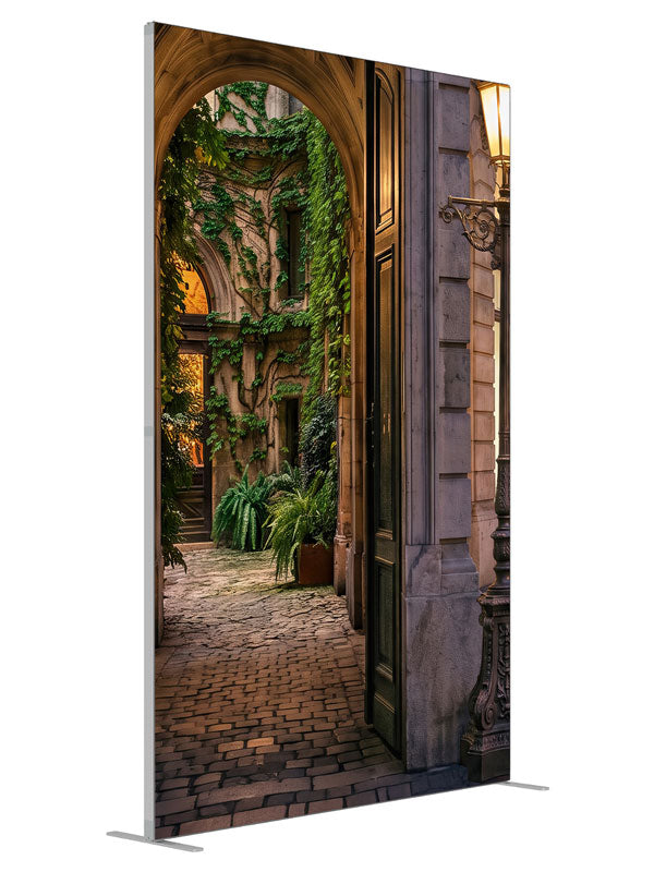 Stone archway opening onto an ivy-covered European courtyard with a glowing iron street lamp, 5ft photography backdrop panel for Denny StudioEdge silicone edge frame, angled view