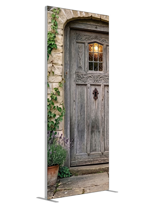 Arched weathered plank cottage door in a honey stone wall with climbing ivy, lavender and potted hydrangeas, 3ft photography backdrop panel for Denny StudioEdge silicone edge frame, angled view