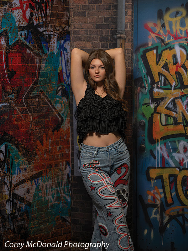 Keaton Graffiti Warehouse Door, photography backdrop panel for Denny StudioEdge silicone edge frame, shown with a senior girl in a black ruffle top posing with arms overhead SECP-8864