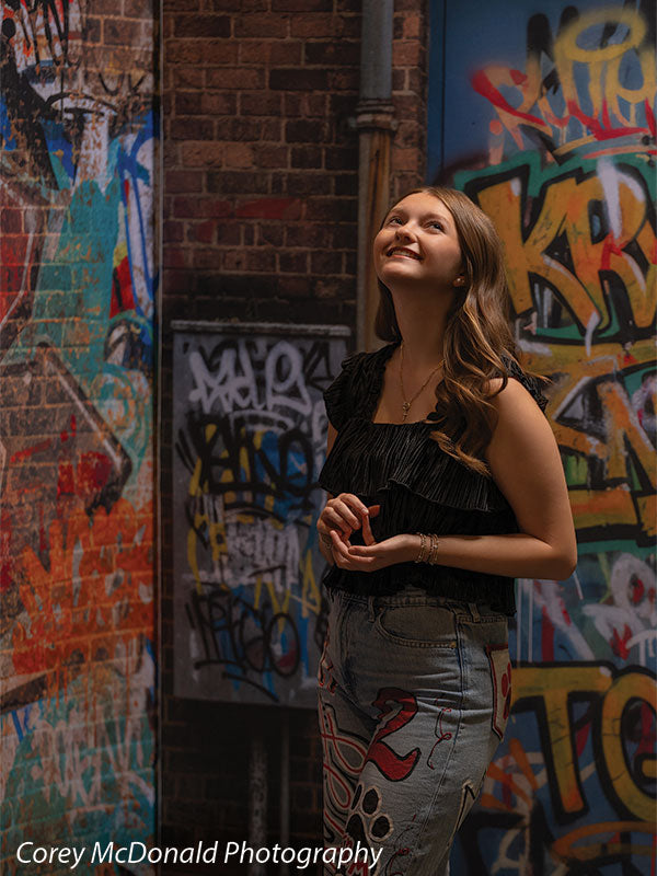 Keaton Graffiti Warehouse Door, photography backdrop panel for Denny StudioEdge silicone edge frame, shown with a senior girl in a black ruffle top looking upward and smiling SECP-8864