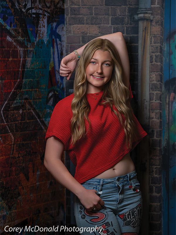 Keaton Graffiti Warehouse Door, photography backdrop panel for Denny StudioEdge silicone edge frame, shown with a senior girl in a red top with an arm resting overhead, smiling SECP-8864
