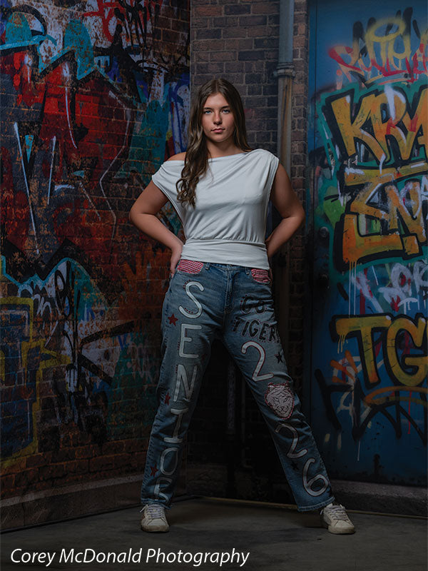 Keaton Graffiti Warehouse Door, photography backdrop panel for Denny StudioEdge silicone edge frame, shown with a senior girl in a white top and painted senior jeans with hands on her hips SECP-8864