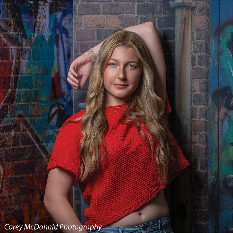 Keaton Graffiti Warehouse Door, photography backdrop panel for Denny StudioEdge silicone edge frame, shown with a senior girl in a red top leaning with an arm overhead on the graffiti wall SECP-8864