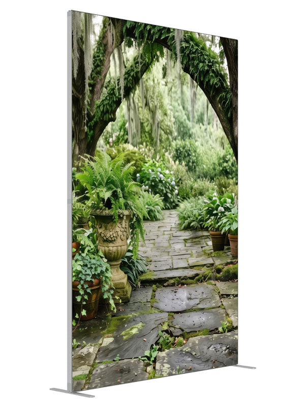 A mossy stone garden path beneath Spanish-moss live oaks with ferns and stone urns, 5ft photography backdrop panel for Denny StudioEdge silicone edge frame, angled view