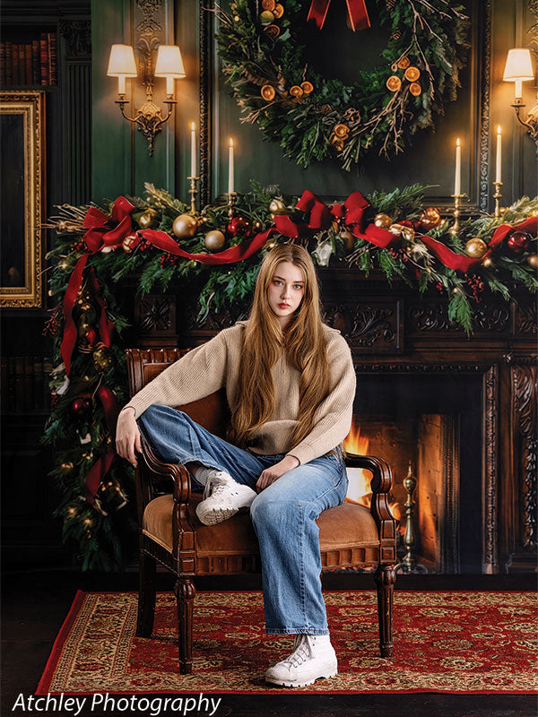 Manor Hearth dark wood fireplace with Christmas wreath photography backdrop shown with a senior girl in a tan sweater and jeans seated in a leather chair CP-8885