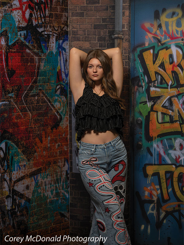 Marlowe Brick Wall Graffiti, photography backdrop panel for Denny StudioEdge silicone edge frame, shown with a senior girl in a black ruffle top posing with arms overhead SECP-8863
