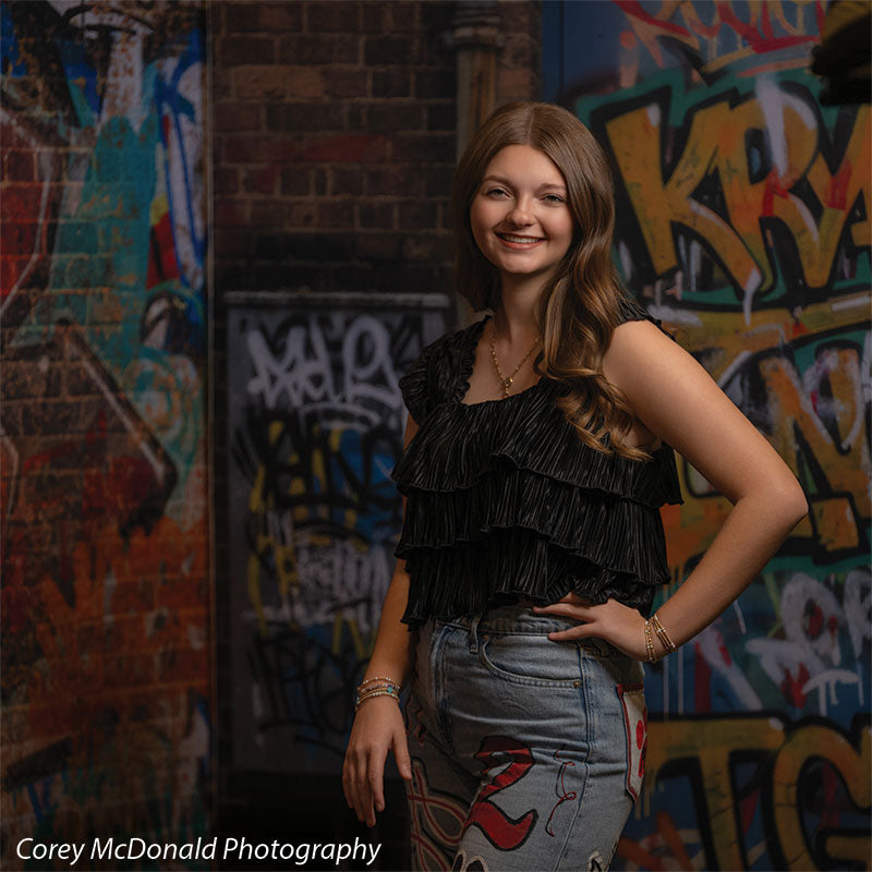 Marlowe Brick Wall Graffiti, photography backdrop panel for Denny StudioEdge silicone edge frame, shown with a senior girl in a black ruffle top with a hand on her hip SECP-8863