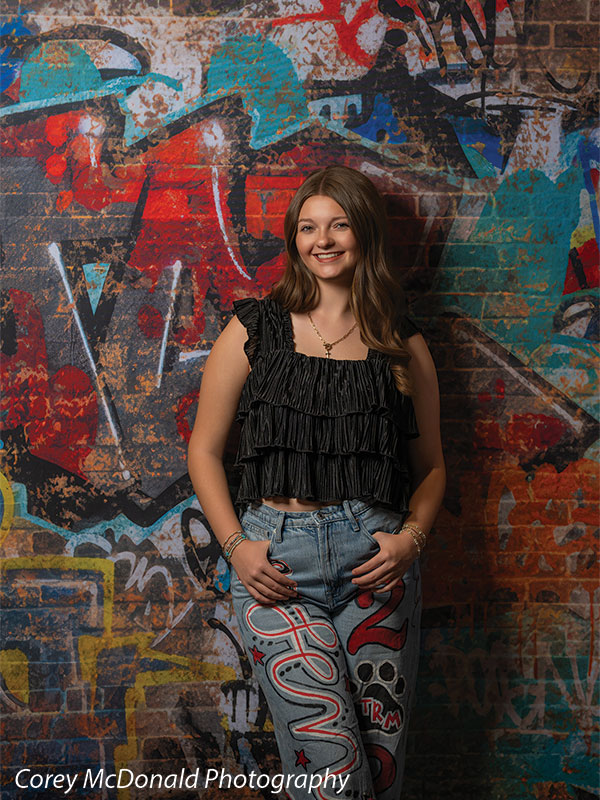 Marlowe Brick Wall Graffiti, photography backdrop panel for Denny StudioEdge silicone edge frame, shown with a senior girl in a black ruffle top standing with hands clasped SECP-8863