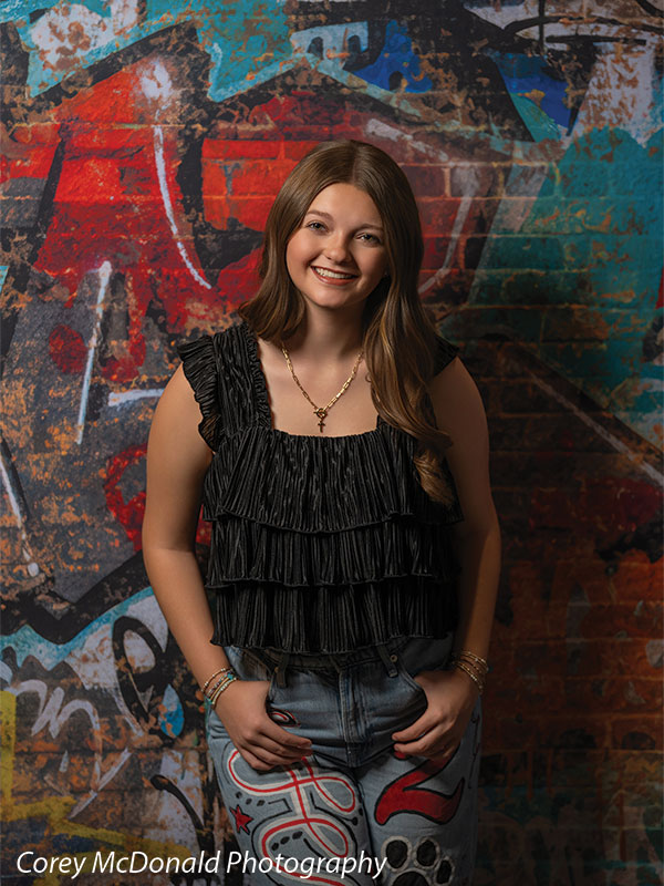 Marlowe Brick Wall Graffiti, photography backdrop panel for Denny StudioEdge silicone edge frame, shown with a senior girl in a black ruffle top smiling, half-length SECP-8863