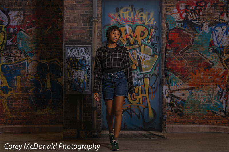 Marlowe Brick Wall Graffiti, photography backdrop panel for Denny StudioEdge silicone edge frame, shown with a senior girl mid-step in front of the graffiti wall SECP-8863