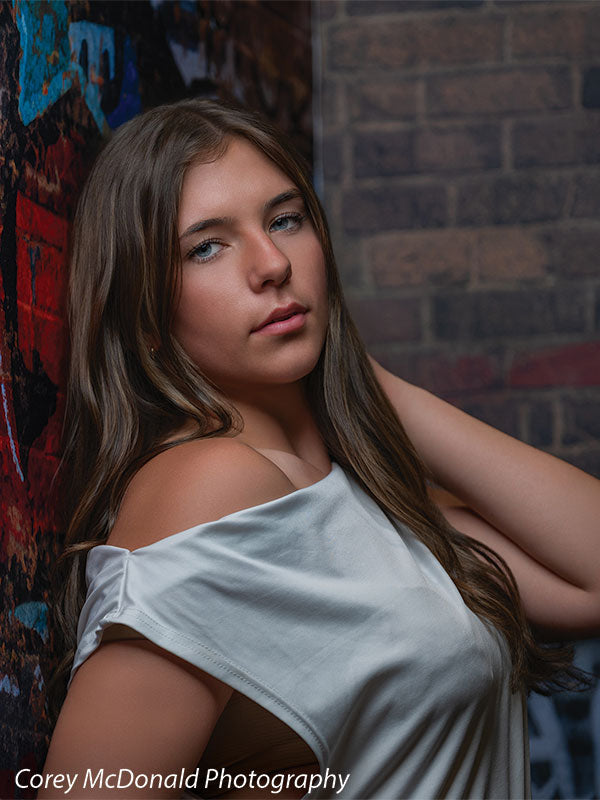 Marlowe Brick Wall Graffiti, photography backdrop panel for Denny StudioEdge silicone edge frame, shown with a senior girl in an off-shoulder white top in a shoulder-framed portrait SECP-8863