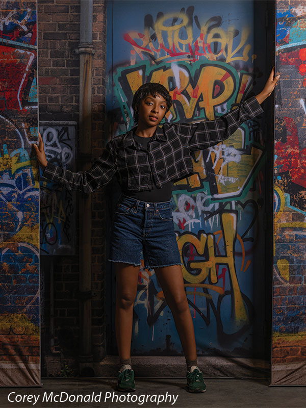 Marlowe Brick Wall Graffiti, photography backdrop panel for Denny StudioEdge silicone edge frame, shown with a senior girl with one arm raised against the graffiti wall SECP-8863