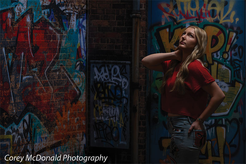 Marlowe Brick Wall Graffiti, photography backdrop panel for Denny StudioEdge silicone edge frame, shown with a senior girl in a red top in profile against the graffiti wall SECP-8863