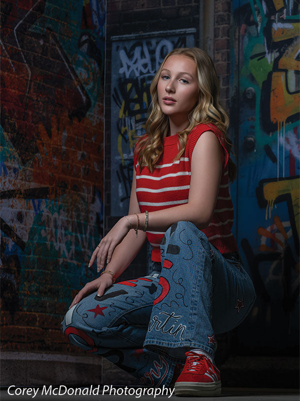 Marlowe Brick Wall Graffiti, photography backdrop panel for Denny StudioEdge silicone edge frame, shown with a senior girl in a red striped top posed kneeling on one knee SECP-8863