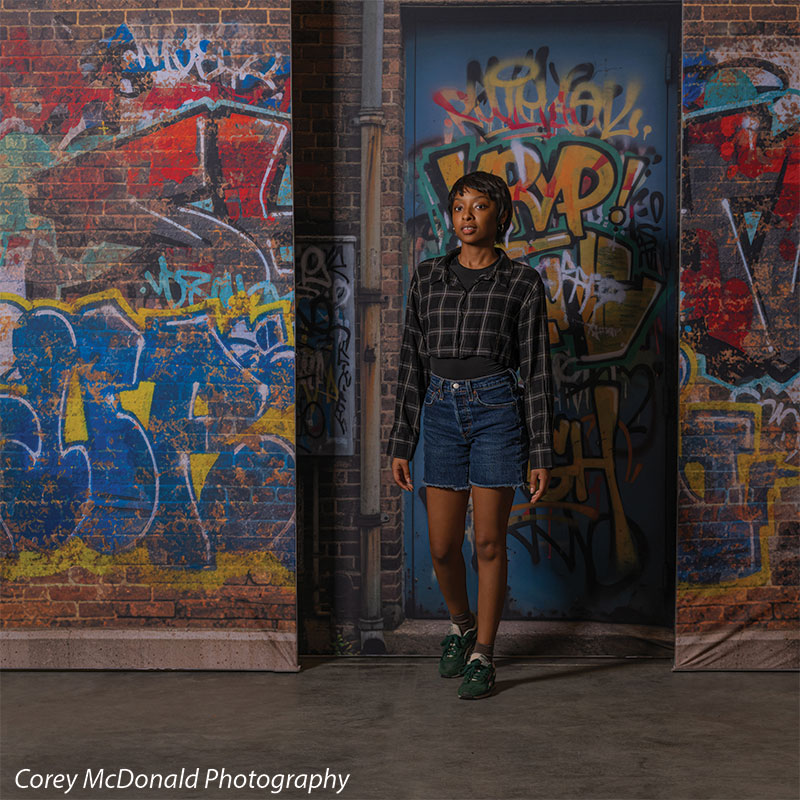 Marlowe Brick Wall Graffiti, photography backdrop panel for Denny StudioEdge silicone edge frame, shown with a senior girl standing centered against the graffiti wall SECP-8863