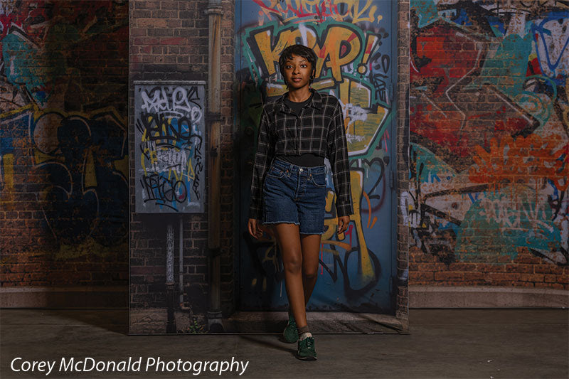 Marlowe Brick Wall Graffiti, photography backdrop panel for Denny StudioEdge silicone edge frame, shown with a senior girl stepping forward in front of the graffiti wall, half-length SECP-8863