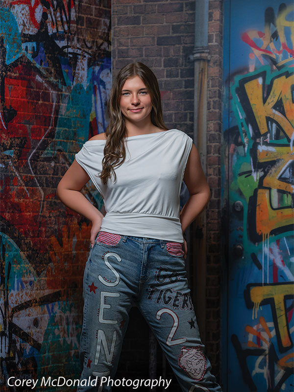 Marlowe Brick Wall Graffiti, photography backdrop panel for Denny StudioEdge silicone edge frame, shown with a senior girl in a white top and painted senior jeans with hands on her hips SECP-8863