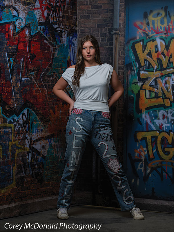 Marlowe Brick Wall Graffiti, photography backdrop panel for Denny StudioEdge silicone edge frame, shown with a senior girl in a white top and painted senior jeans with hands on her hips SECP-8863