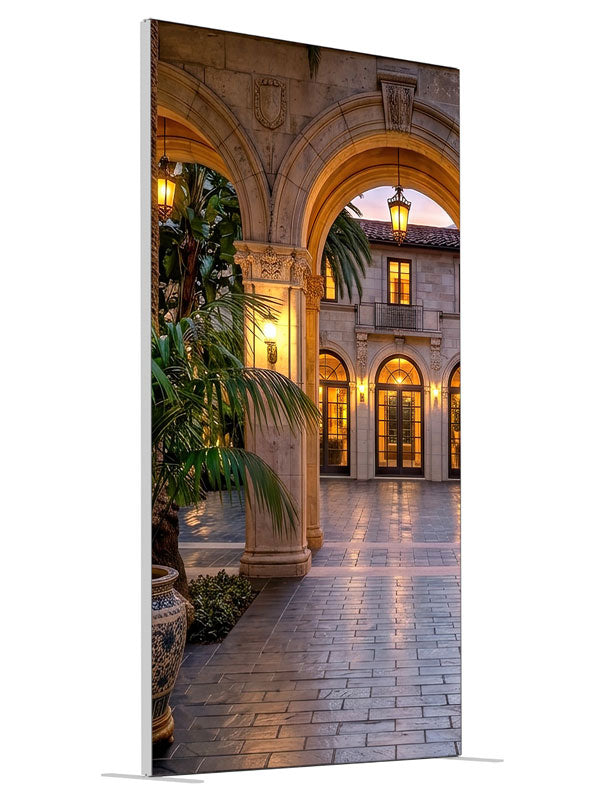 Grand stone archways opening onto a lantern-lit Mediterranean villa courtyard at dusk, 4ft photography backdrop panel for Denny StudioEdge silicone edge frame, angled view