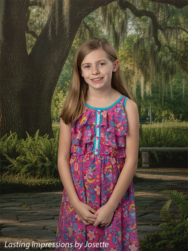 Moss Oak photography backdrop showing a grand Southern live oak draped in Spanish moss over a stone garden path, shown with a young girl in a pink floral dress with hands clasped CP-8783