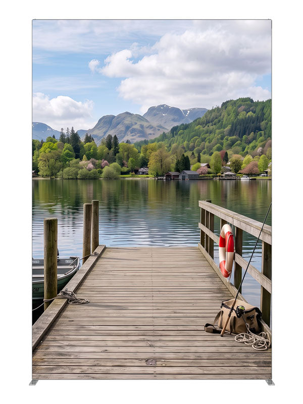 Weathered wooden dock running out into a calm mountain lake with a moored rowboat and a forested far shore, 5ft photography backdrop panel for Denny StudioEdge silicone edge frame