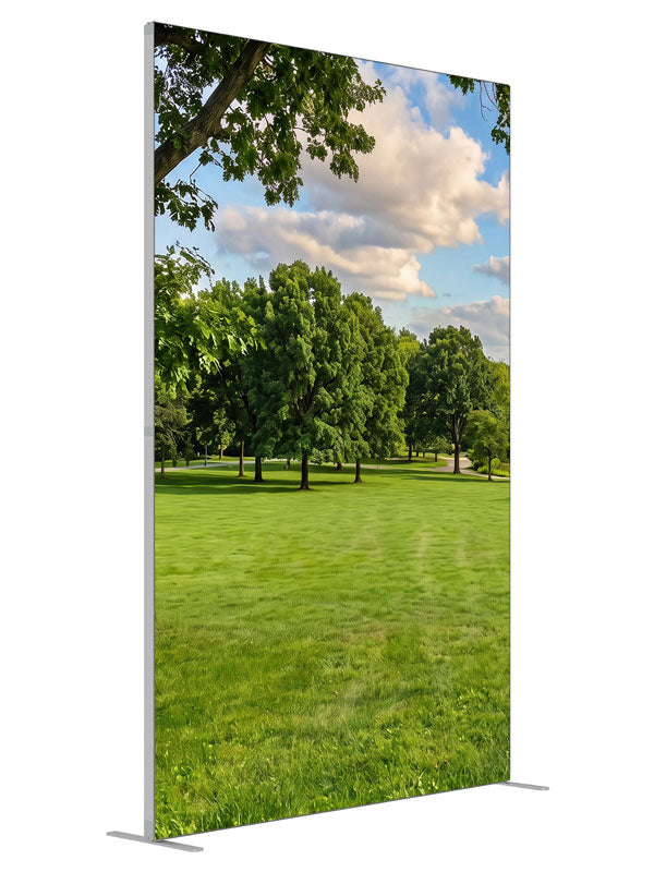 A broad open park lawn with a large shade tree and a distant tree line under a cloud-dotted sky, 5ft photography backdrop panel for Denny StudioEdge silicone edge frame, angled view