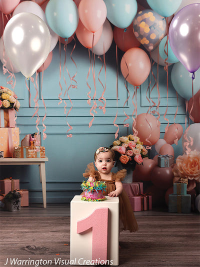 Baby girl celebrating birthday with mini cake in front of Peach Balloon Bliss Cake Smash Backdrop full of balloons and flowers.