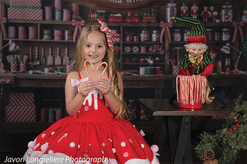 Peppermint Hollow Santa's peppermint workshop photography backdrop shown with a young girl in a red-and-white candy dress seated holding a candy-cane heart, wide view CP-8912