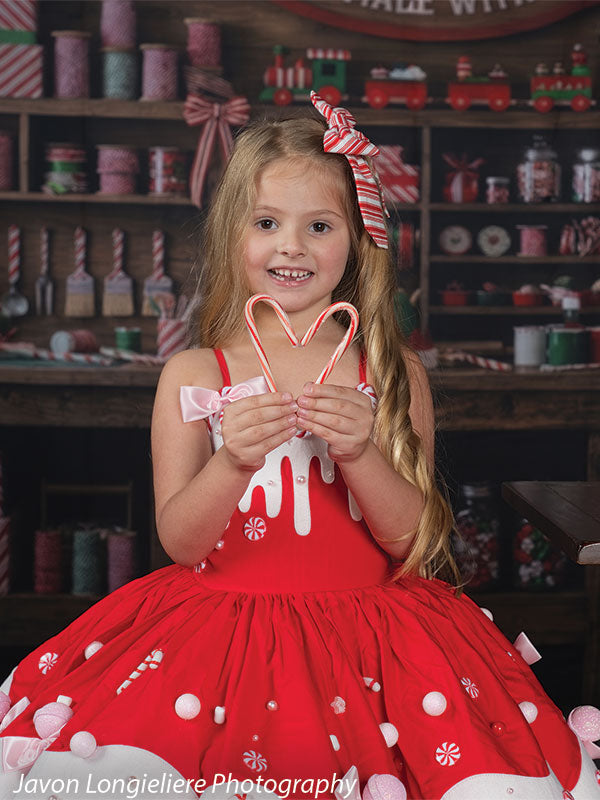 Peppermint Hollow Santa's peppermint workshop photography backdrop shown with a young girl in a red-and-white candy dress standing with a candy-cane heart CP-8912