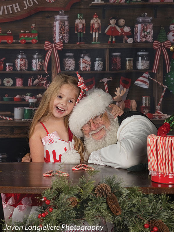 Peppermint Hollow Santa's peppermint workshop photography backdrop shown with a young girl in a candy dress beside Santa at the workshop table CP-8912