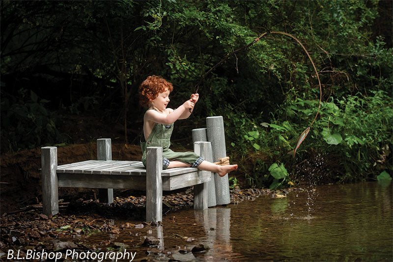 Pier and piling beach prop set shown with a red-haired toddler in green overalls casting the twig fishing line into the creek from the pier BEACH-SET