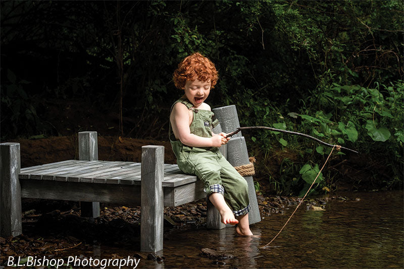 Pier and piling beach prop set shown with a red-haired toddler in green overalls laughing while fishing off the gray wooden pier beside the piling posts BEACH-SET