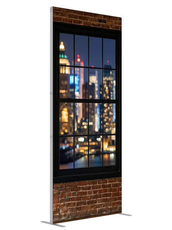 A red-brick industrial loft with black-framed windows over a nighttime city skyline in bokeh, 3ft photography backdrop panel for Denny StudioEdge silicone edge frame