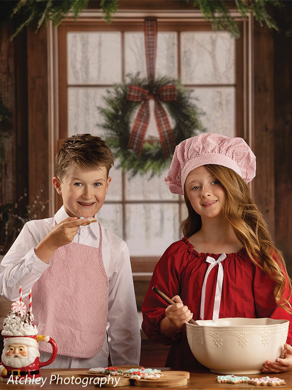 Red Cabin rustic Christmas kitchen photography backdrop shown with a boy and girl in aprons baking together in a close portrait CP-8887