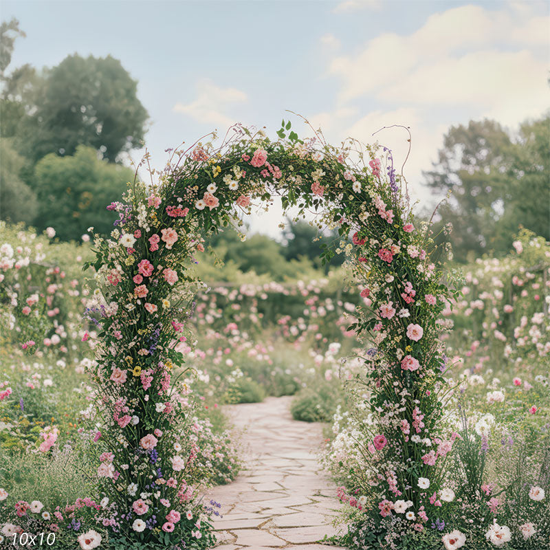 Soft pink and lavender flowers line a natural stone walkway beneath a dreamy floral arch.