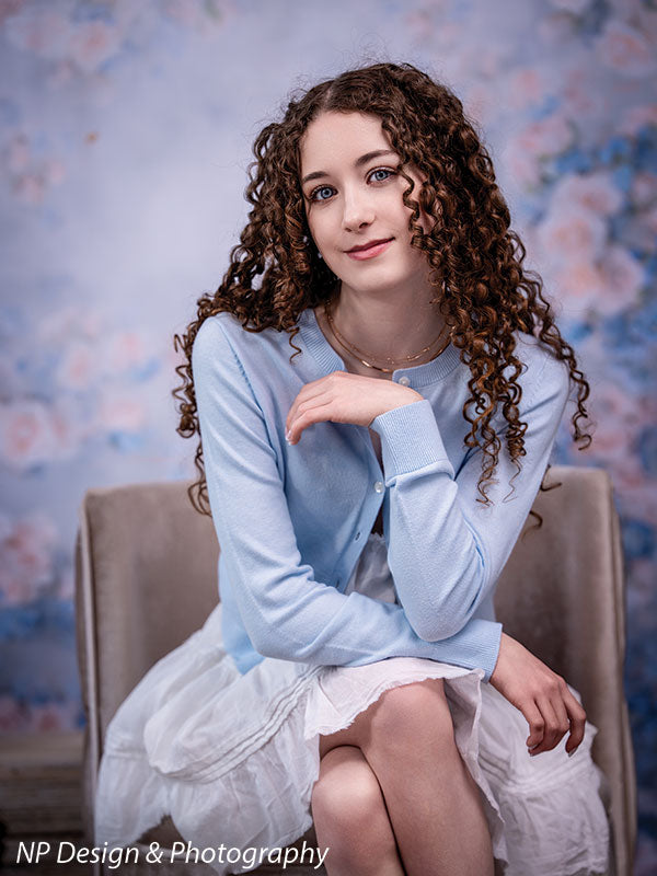 Rose master blue floral photography backdrop shown with seated with her hand resting near her chin CP-7598