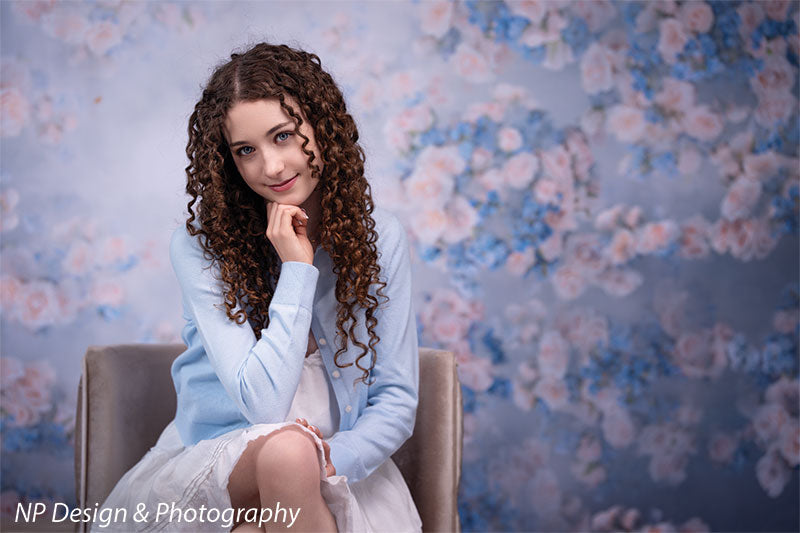 Rose master blue floral photography backdrop shown with seated in a chair with her hand to her chin and a soft smile CP-7598
