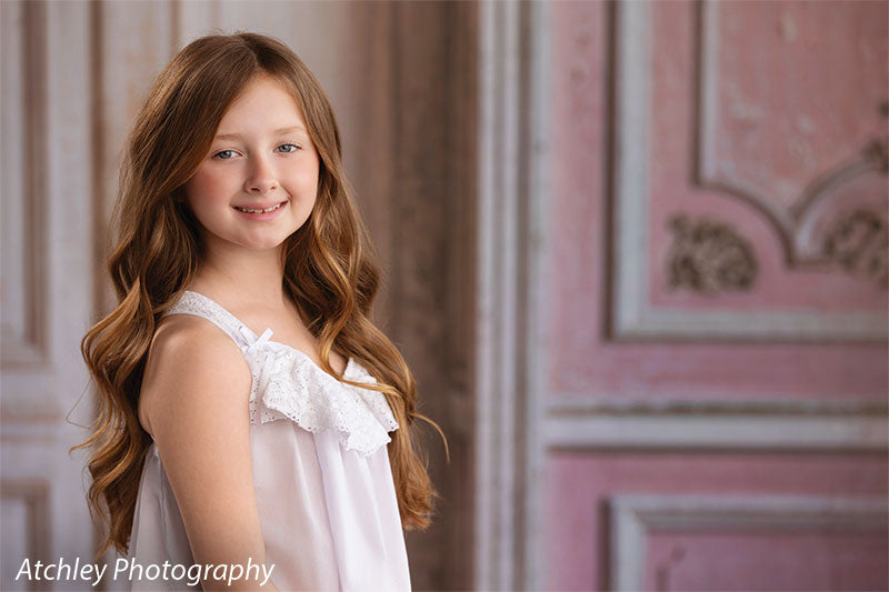 Rose Parlor distressed pink French double doors photography backdrop shown with a young girl in a white slip dress smiling in a half-length view CP-8793