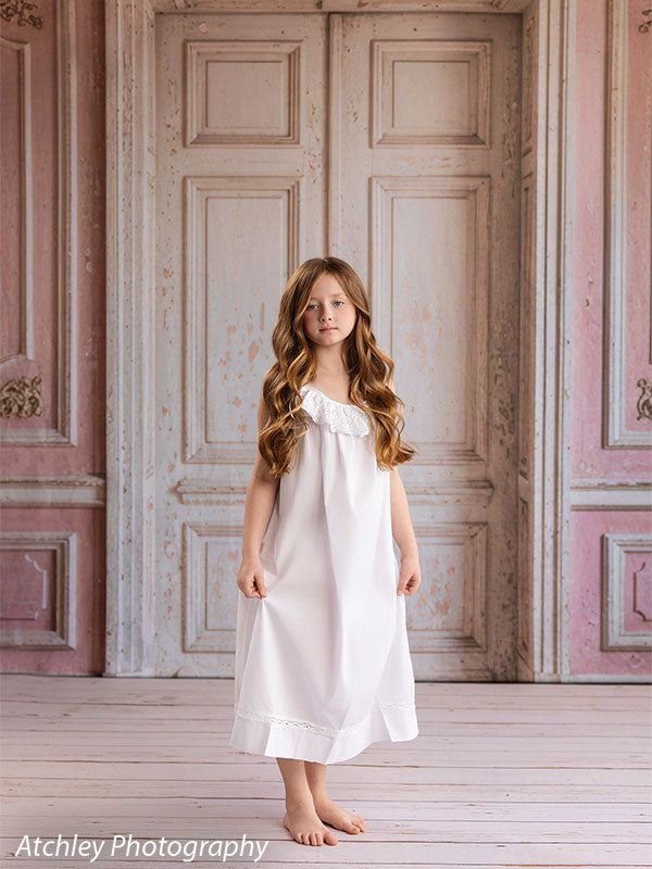 Rose Parlor distressed pink French double doors photography backdrop shown with a young girl standing full-length in a white slip dress CP-8793