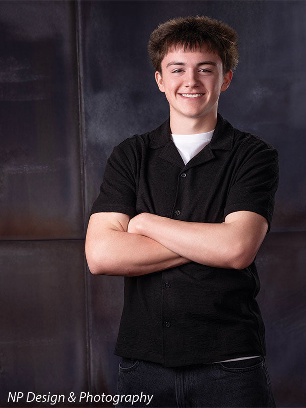 Rustic industrial metal panels photography backdrop shown with a senior boy with his arms crossed in a vertical portrait CP-8431