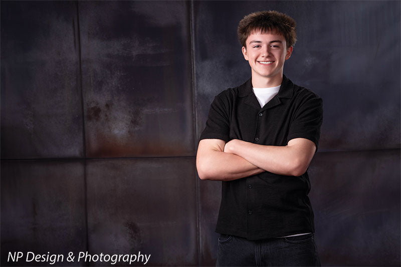 Rustic industrial metal panels photography backdrop shown with a senior boy standing with his arms crossed, smiling CP-8431