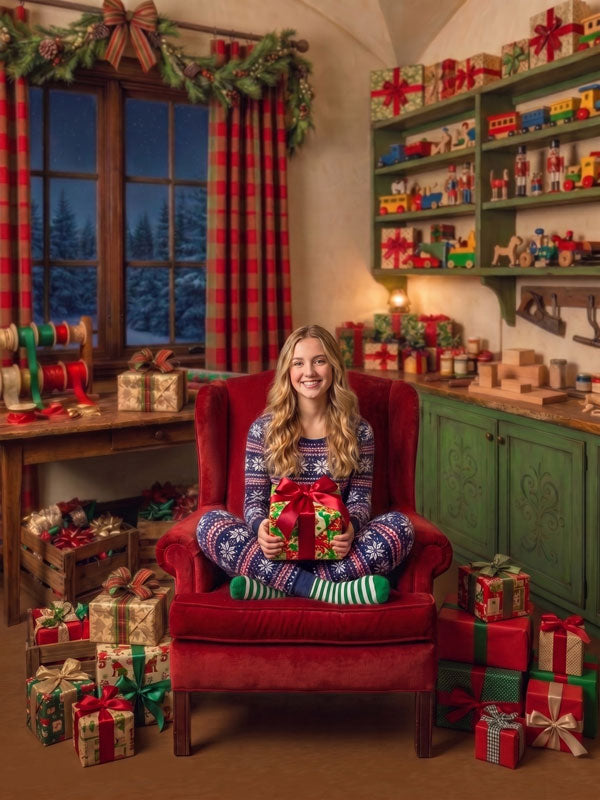 Sage Noel Santa's workshop with ornate green cabinets photography backdrop shown with a teen girl in fair-isle pajamas seated in a red wingback chair holding a gift CP-8915